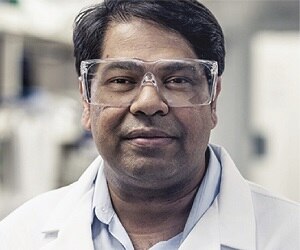 A scientist wearing safety glasses and a lab coat.