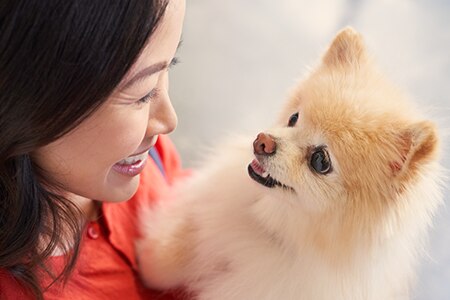 A woman holding her dog and smiling.